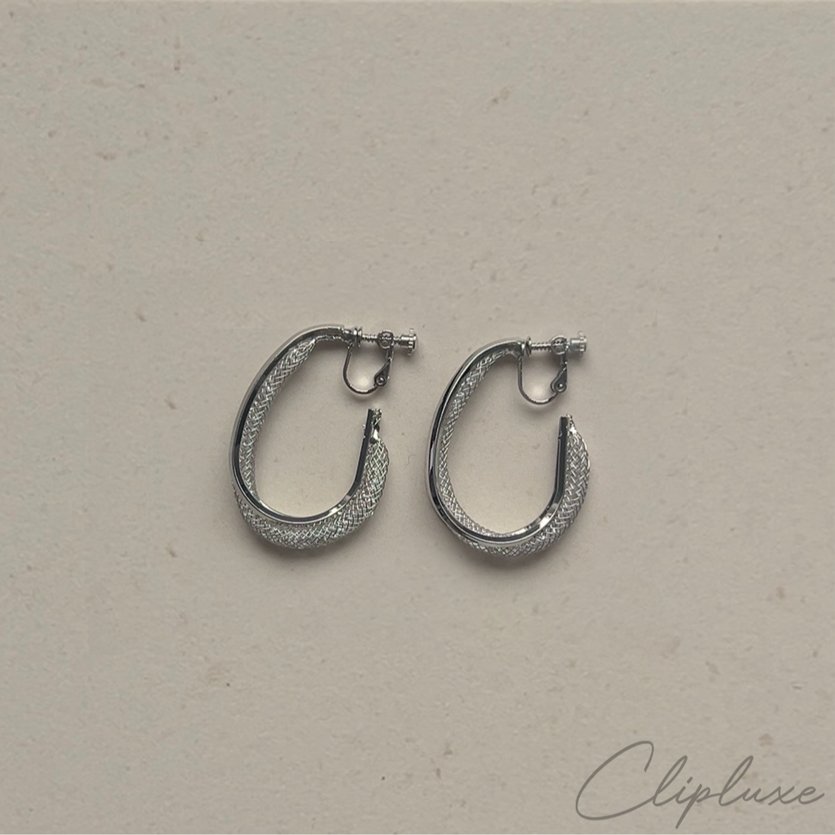 Silver hoop earrings on a beige background with 'Clipluxe' branding.